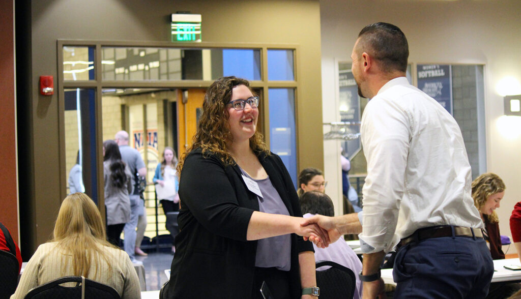 51student shakes hands with school district representative during Career Interview Fair